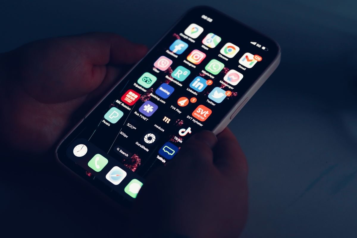 A hand holding a phone showing apps with notifications in the dark