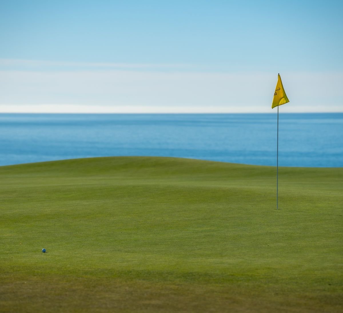 Links green with a flag set right above the ocean