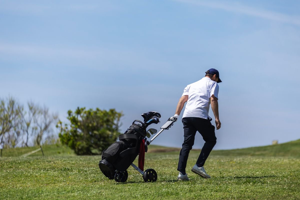 Golfer pulling his own golf trolley and bag across the fairway