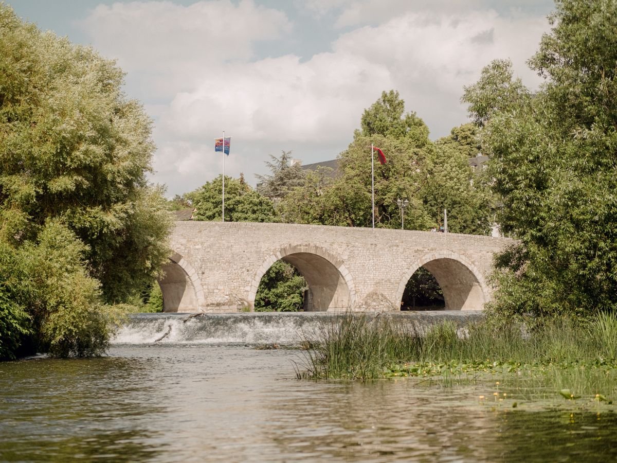 A stone arch bridge over the calm green River Suir in Tipperary