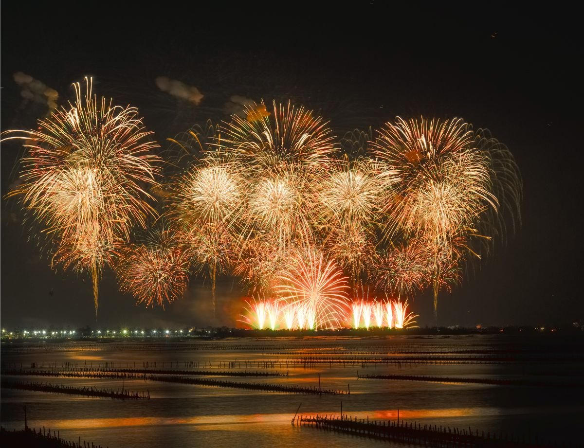 Fireworks bursting over dark water on Halloween night