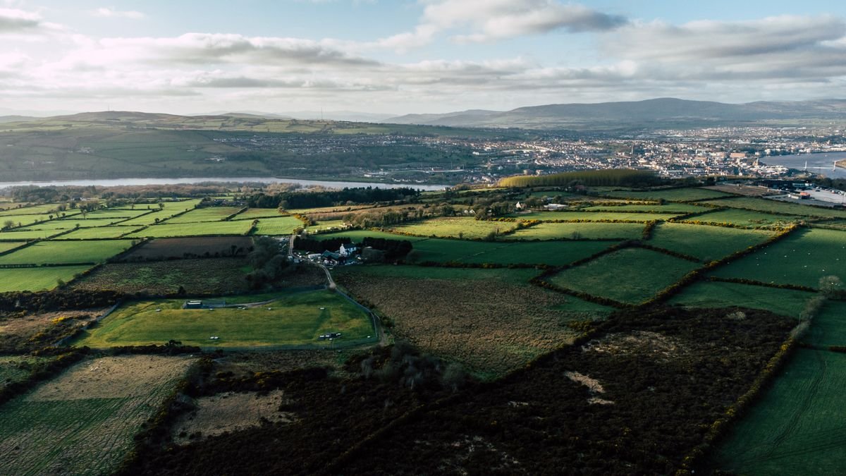 Aerial view of green patchwork fields and a river across the Irish countryside
