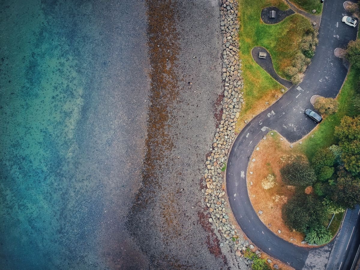 An aerial view of a small coastal car park by the shore