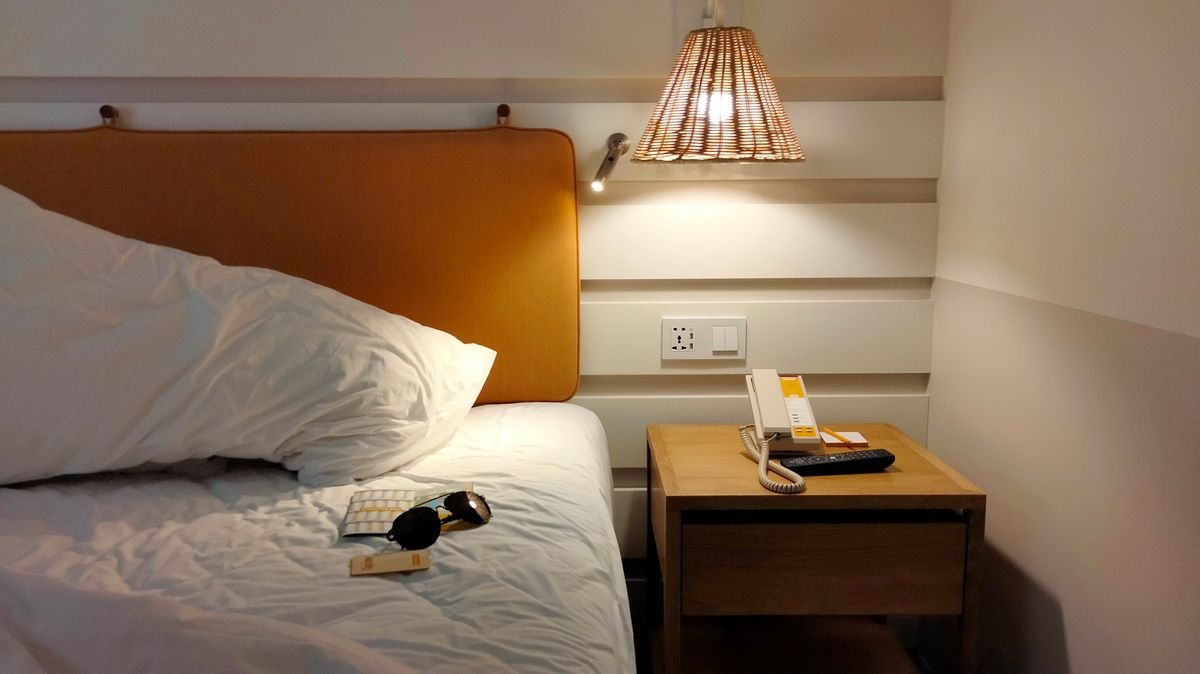 A clean modern hotel room with a made bed and bedside table