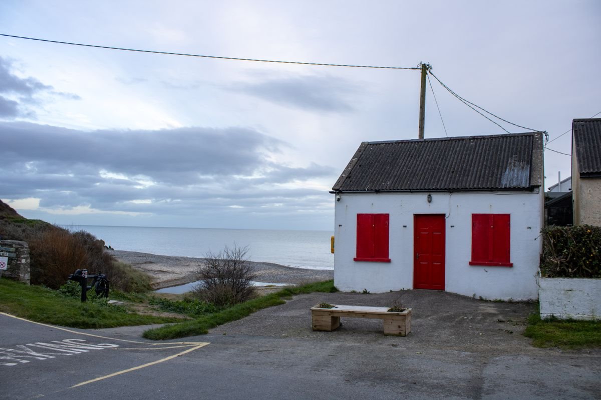 A whitewashed coastal cottage beside a beach