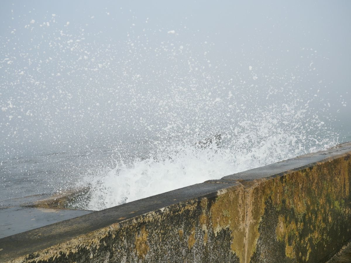 Sea spray crashing over a concrete promenade seawall