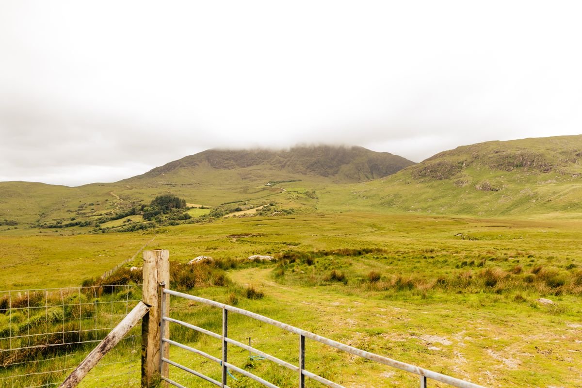 Low cloud rolling over green Irish hills with a farm gate in the foreground