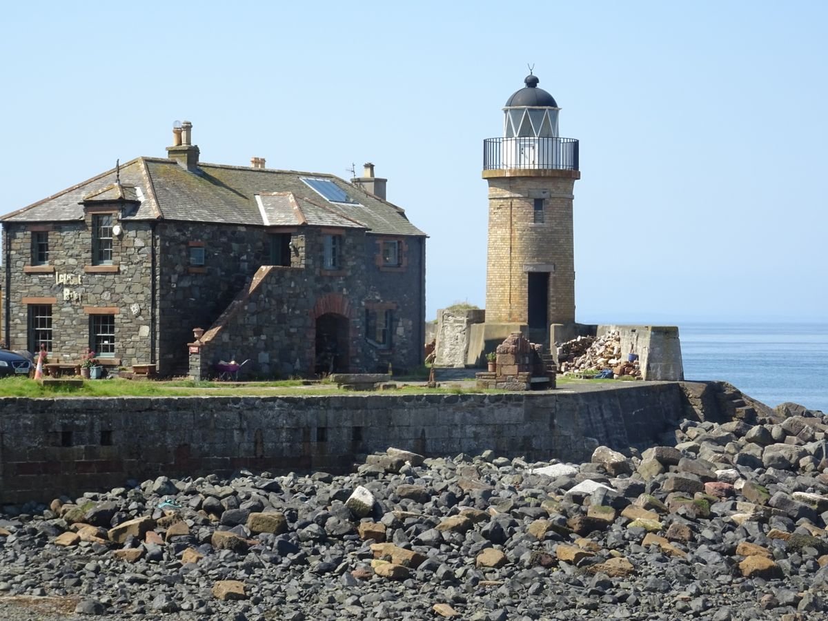 Stone lighthouse keeper's house beside a small lighthouse tower