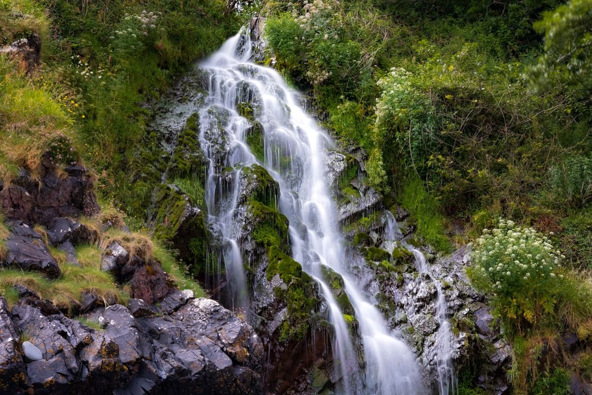 Wide fan-shaped waterfall over mossy rock
