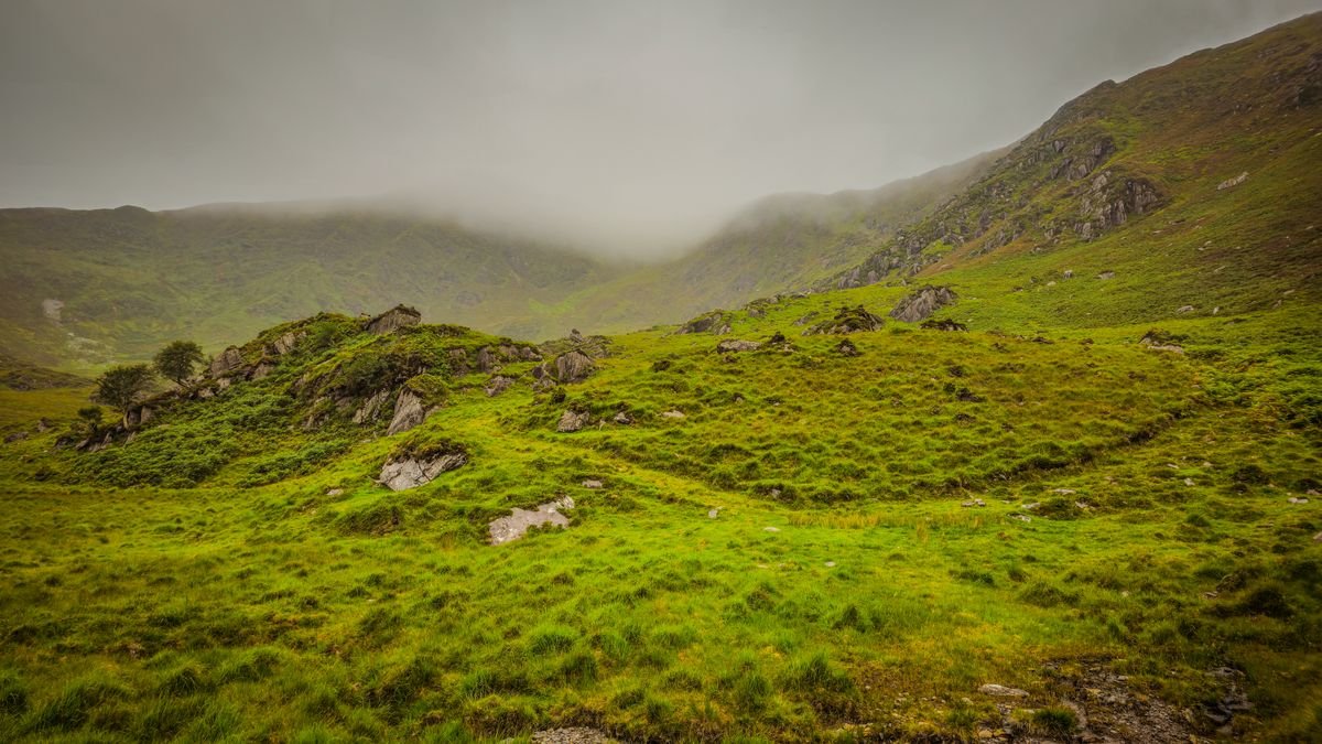Green Irish mountain valley under low cloud and rain