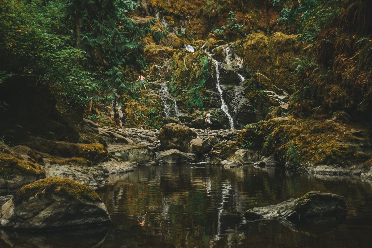 People on the rocks around a waterfall pool in Ireland