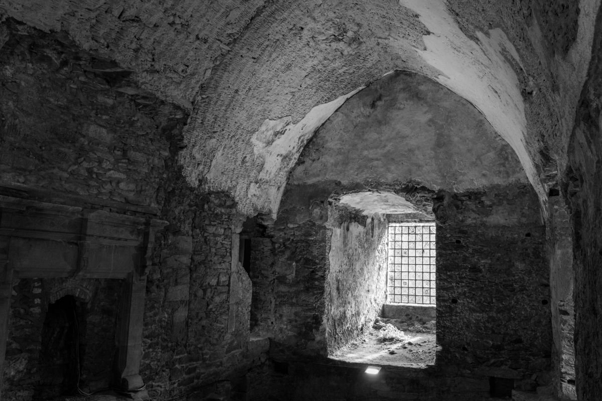The vaulted stone interior of a ruined Irish castle lit by a single window