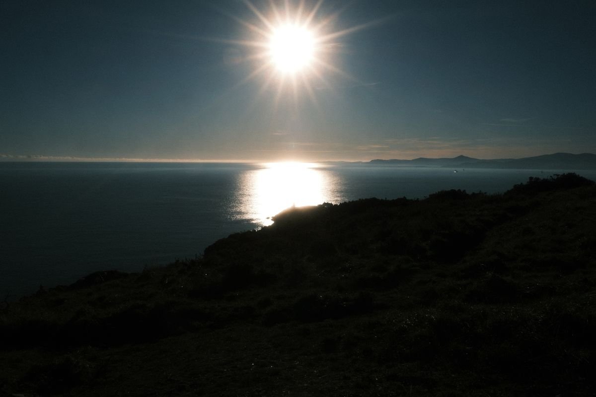 The sun low over the sea on an Irish clifftop at the end of the day