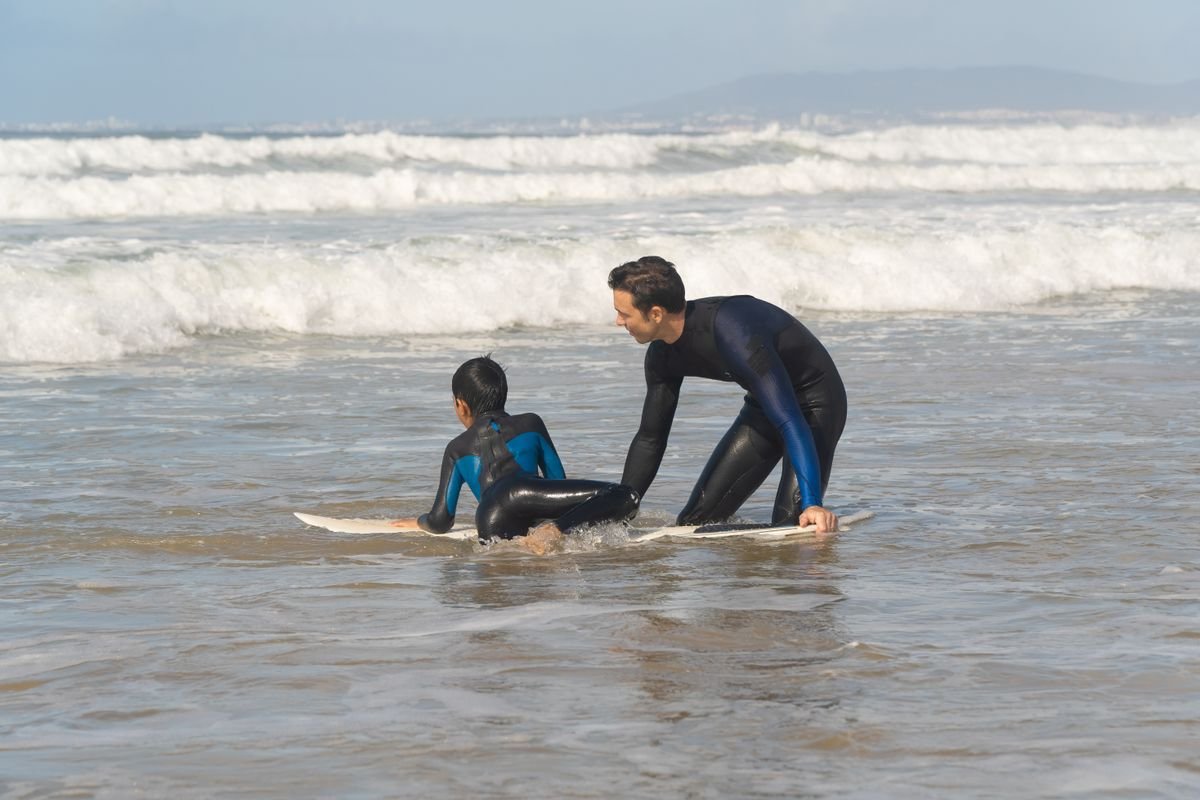 Surf instructor teaching a beginner in the whitewater at a beach