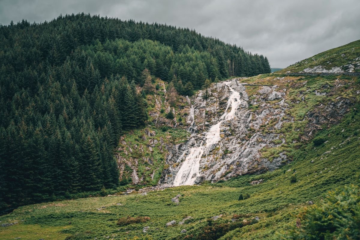 Waterfall streaming down a rocky forested hillside in Ireland
