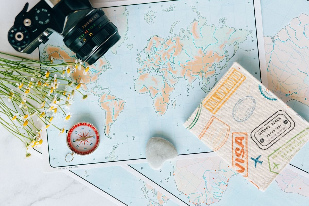 A travel planning flatlay with a world map and compass