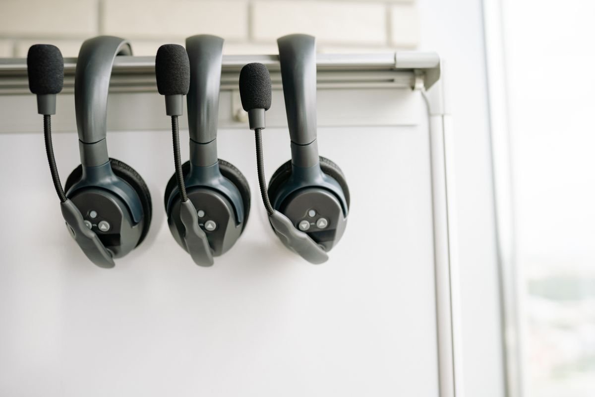 Three tour-guide audio headsets hanging on a rail