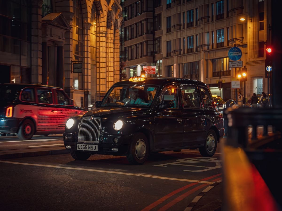 A classic black cab on a city street at night