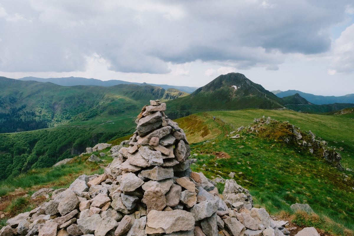 A large pile of loose stones forming a cairn on a green mountain summit