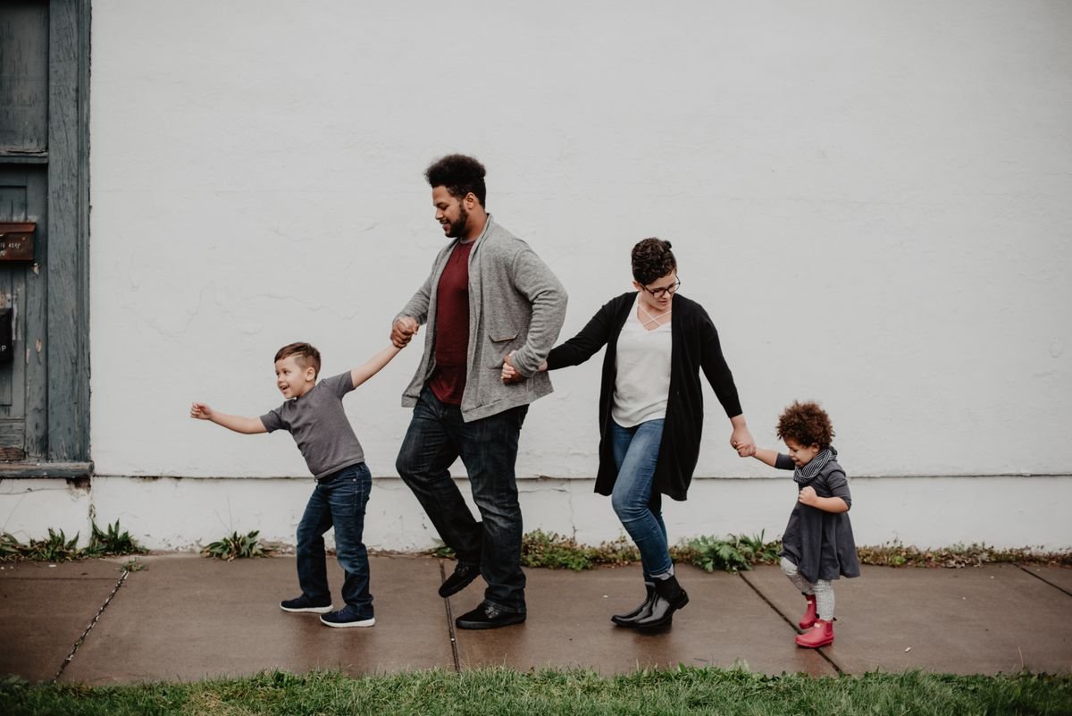 A family of four walking hand in hand along a path