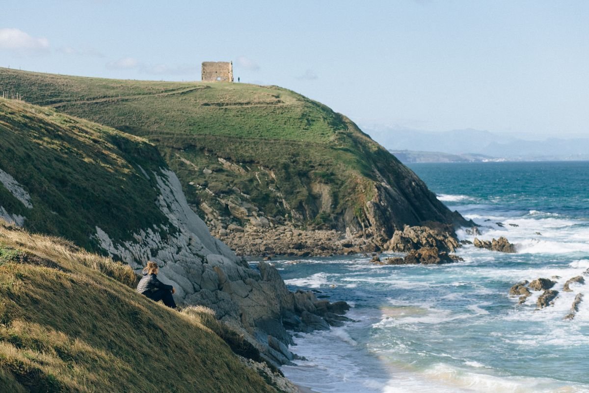 old stone signal hut on a green headland above the sea