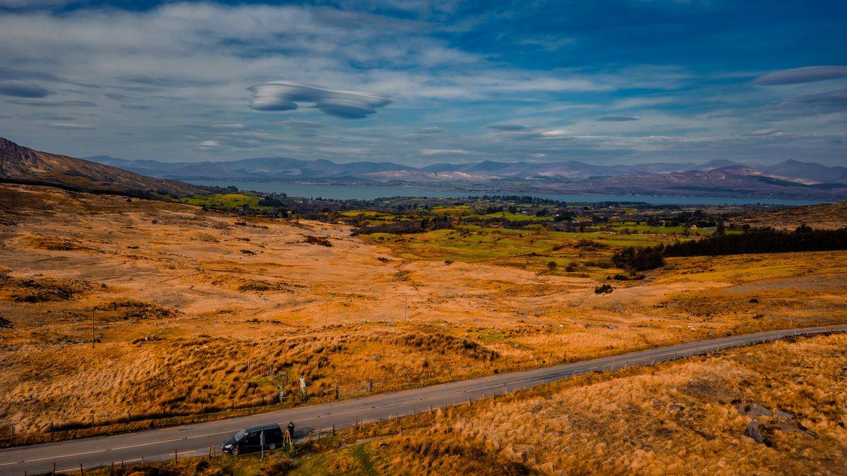A car on the Ring of Kerry coast road with mountains behind