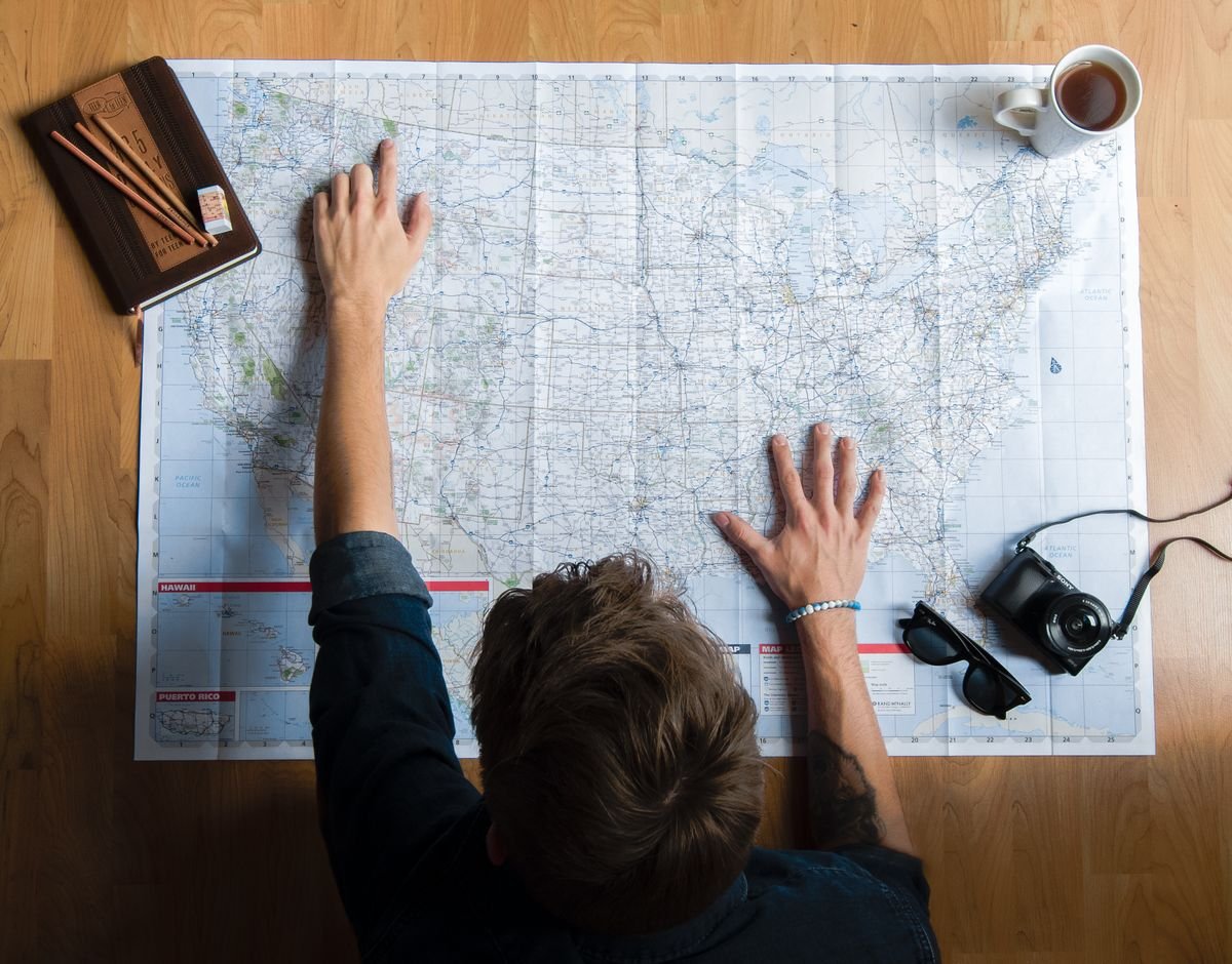 Travel planner working out trip length over a map and notebook