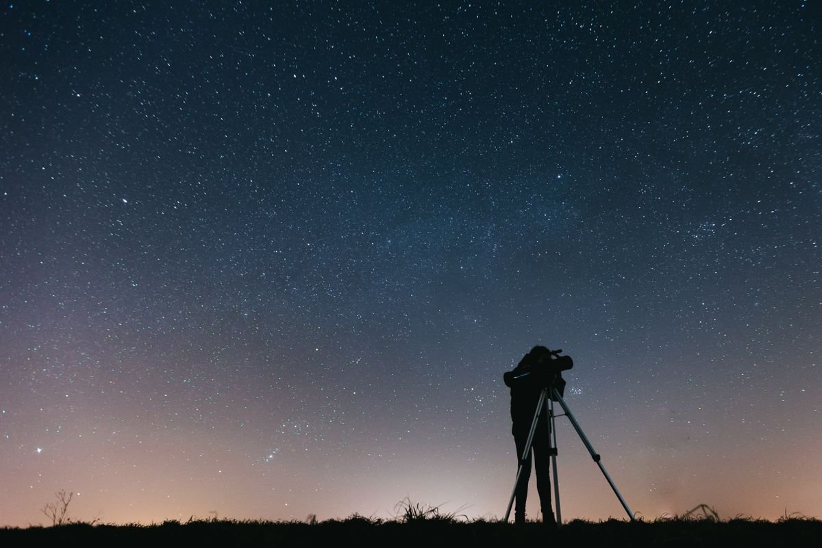 Person with a telescope stargazing under the Milky Way