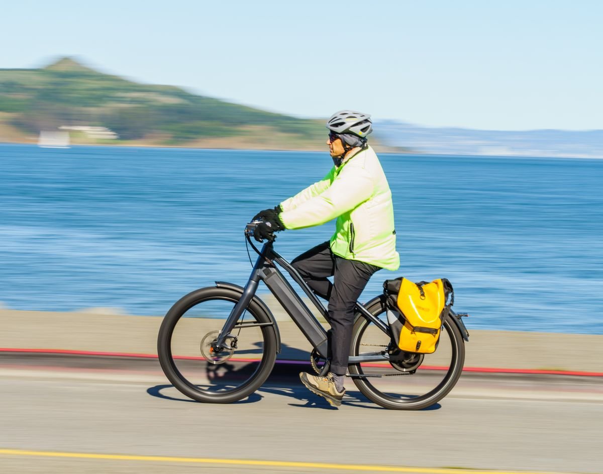 Cyclist with a pannier bag riding a coastal greenway path