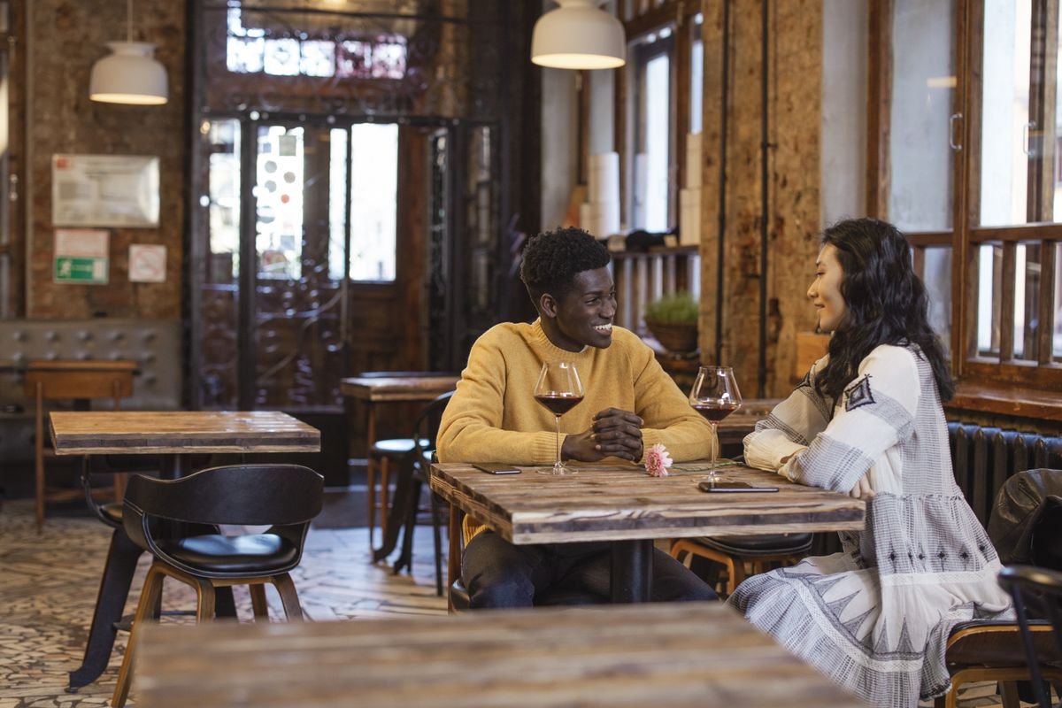 Couple sharing red wine at a small casual bistro with brick walls