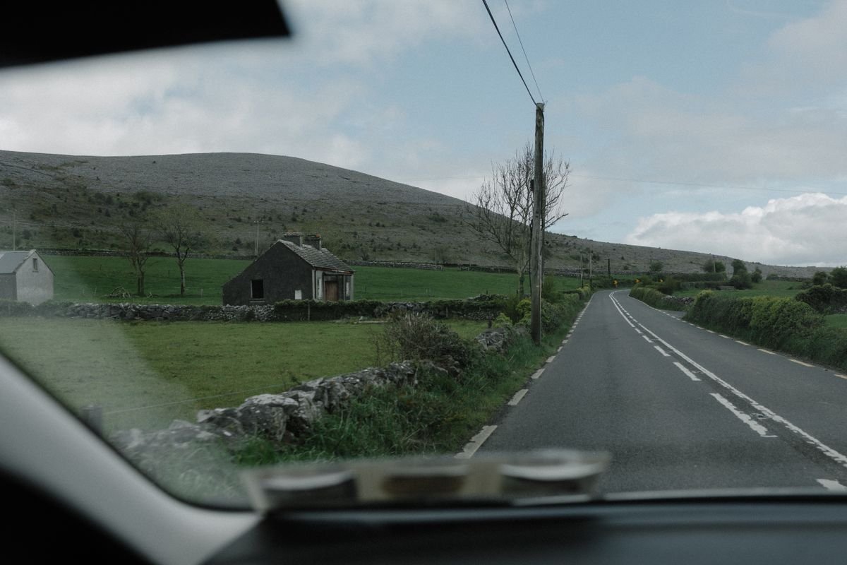View through a windscreen of a narrow rural Irish road with stone walls