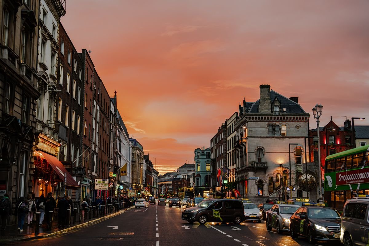 A Dublin city centre street at sunset with taxis and a bus