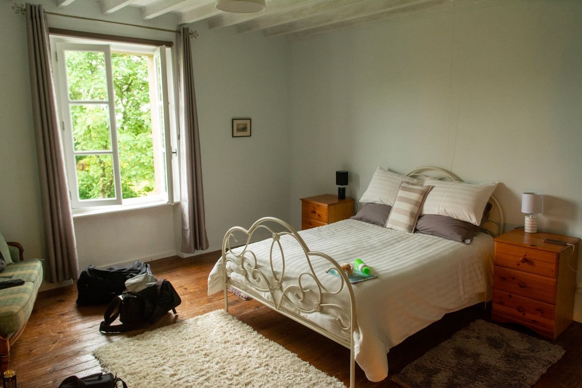 Irish bed and breakfast bedroom with a white iron bed, wooden floor and open window.