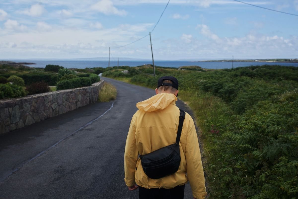 Narrow rural Irish road running out to the coast with a stone wall