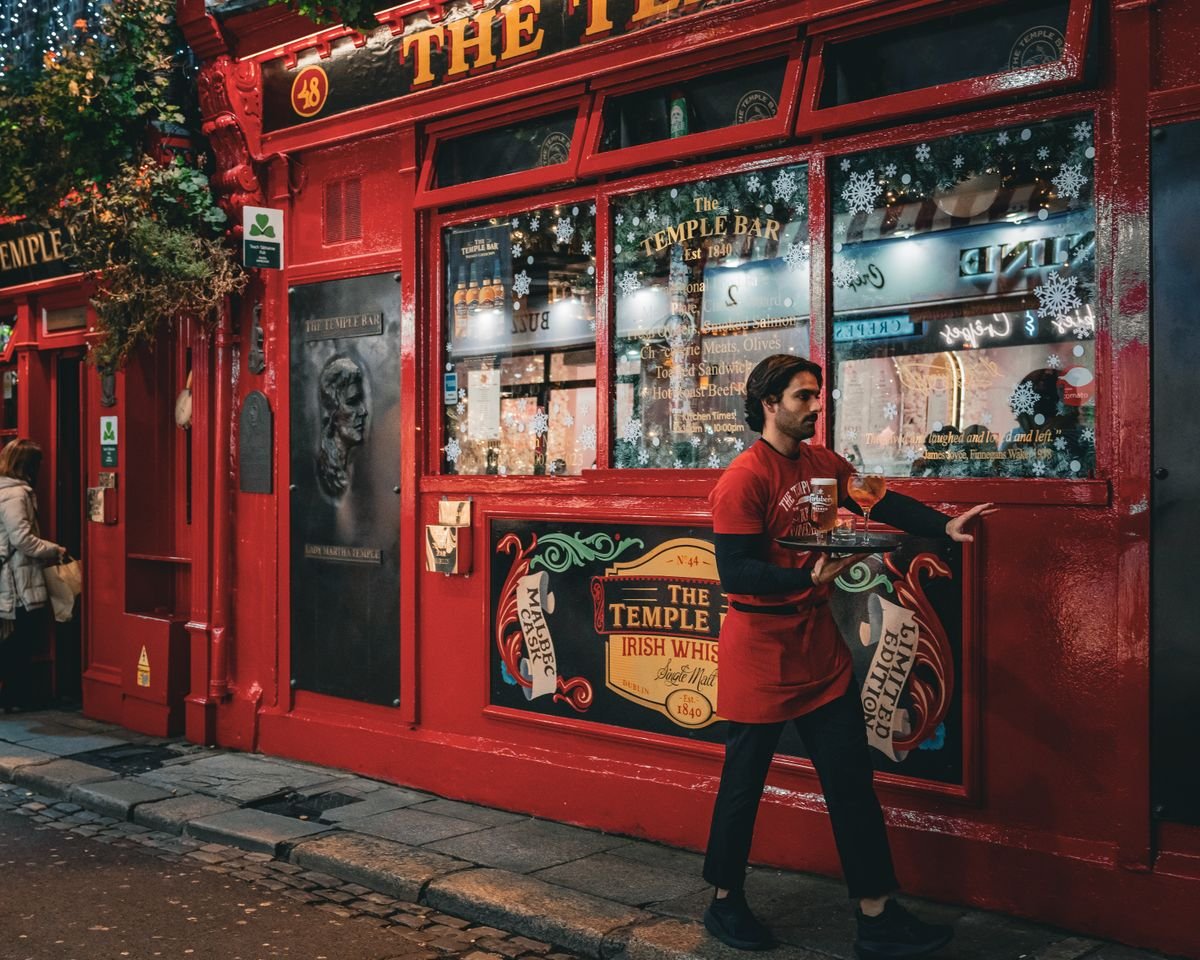 The red front of the Temple Bar pub in Dublin with a waiter passing