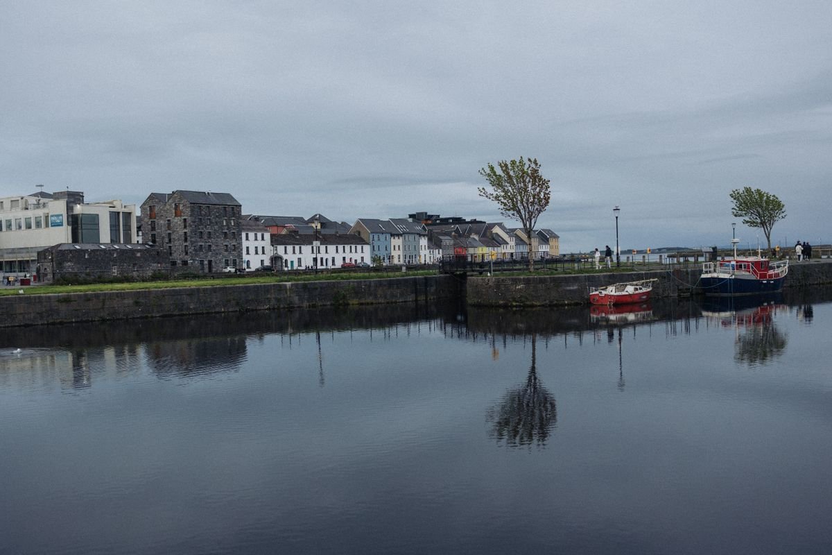 Colourful houses reflected in the water along the Long Walk in Galway