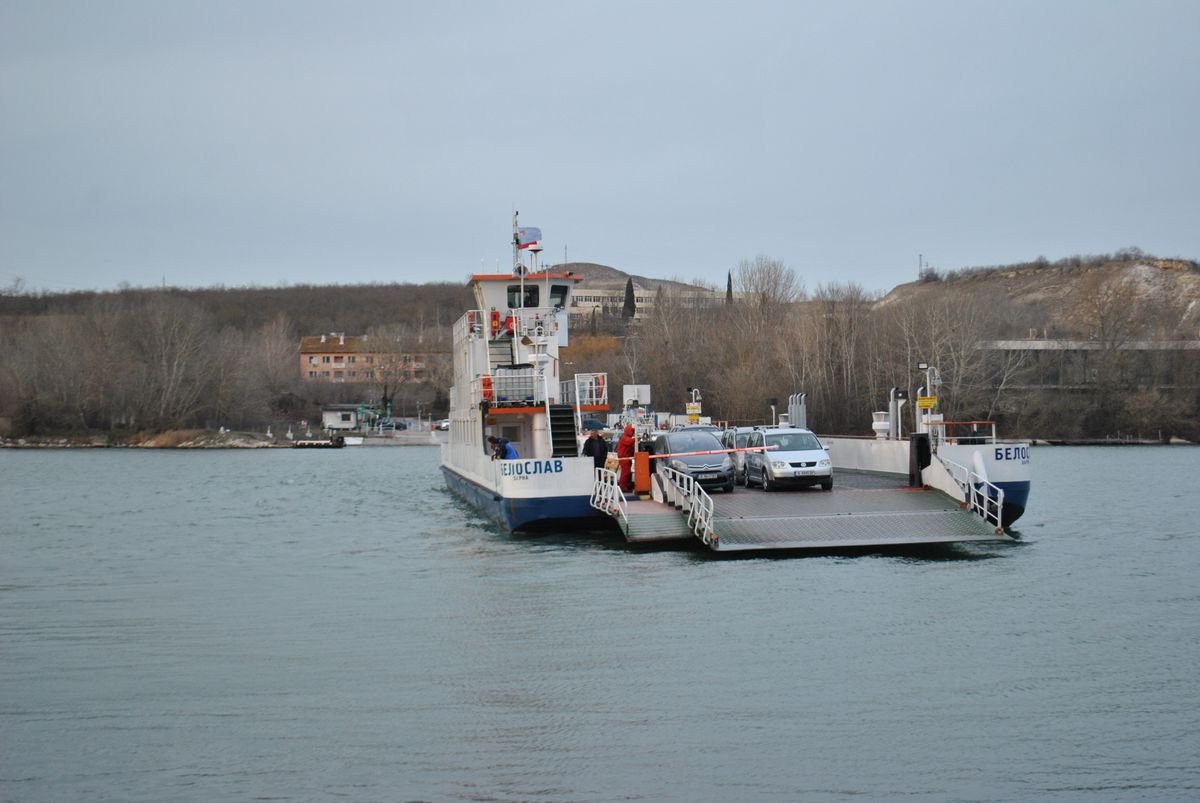 Car ferry loaded with vehicles crossing calm estuary water
