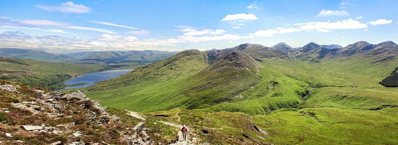 A hiker on a trail above a lake in the Connemara mountains