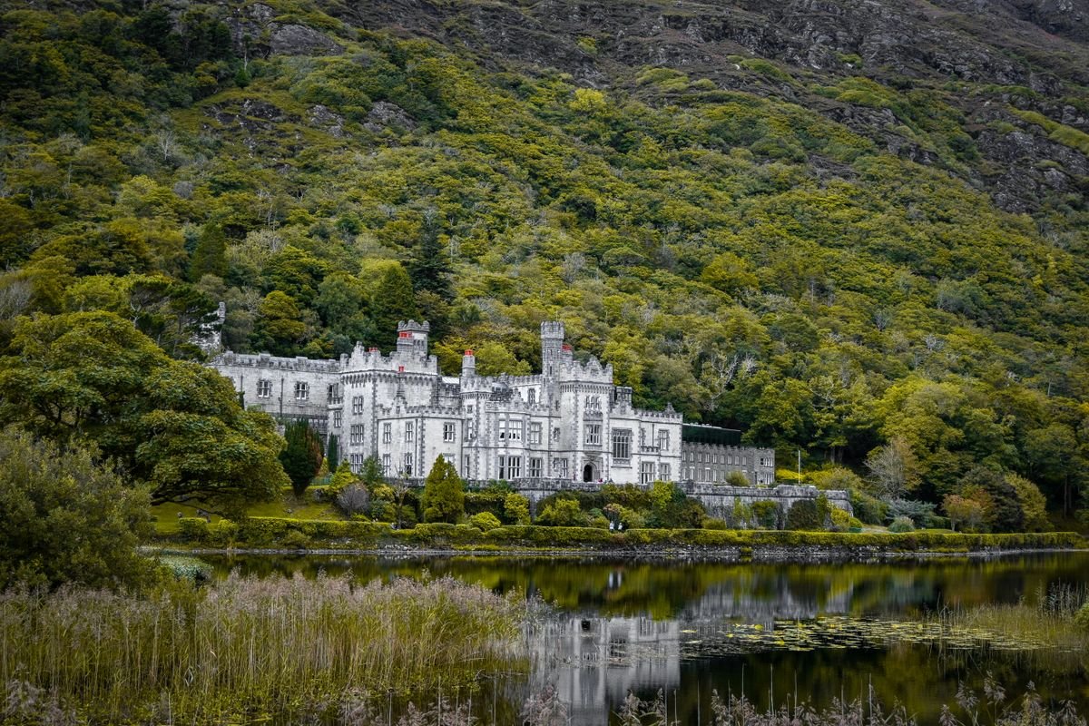 Kylemore Abbey reflected in the lake below its wooded hillside in Connemara.