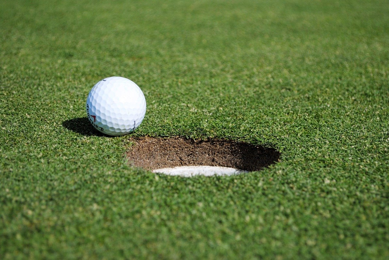 A golf ball resting on the lip of the hole on a green