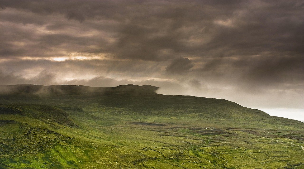 Wide green Irish moorland and mountain landscape under a brooding sky