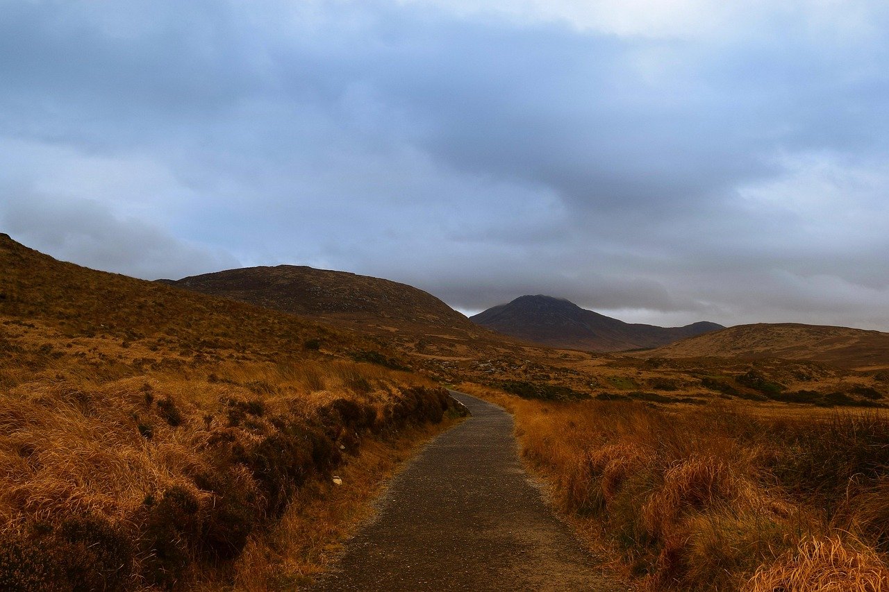 Path winding through moody Irish mountains under a grey sky