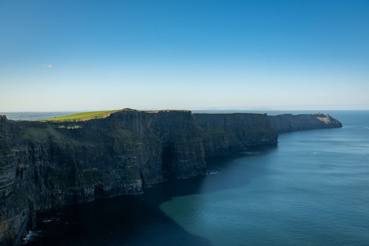 Wide clifftop view of the Cliffs of Moher in County Clare with O'Brien's Tower on the headland and the Atlantic below