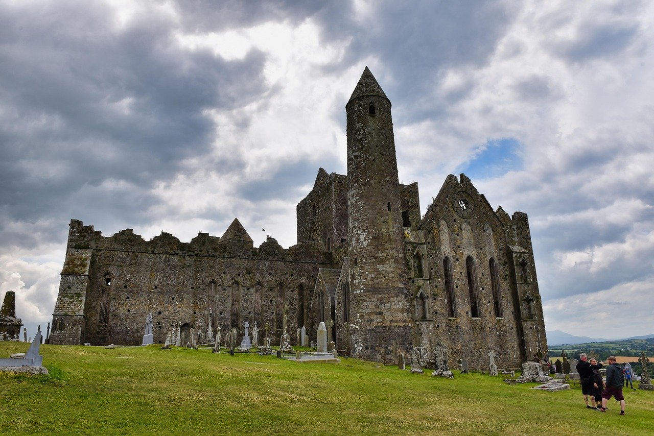 The medieval buildings and round tower of the Rock of Cashel on their outcrop under a dramatic sky