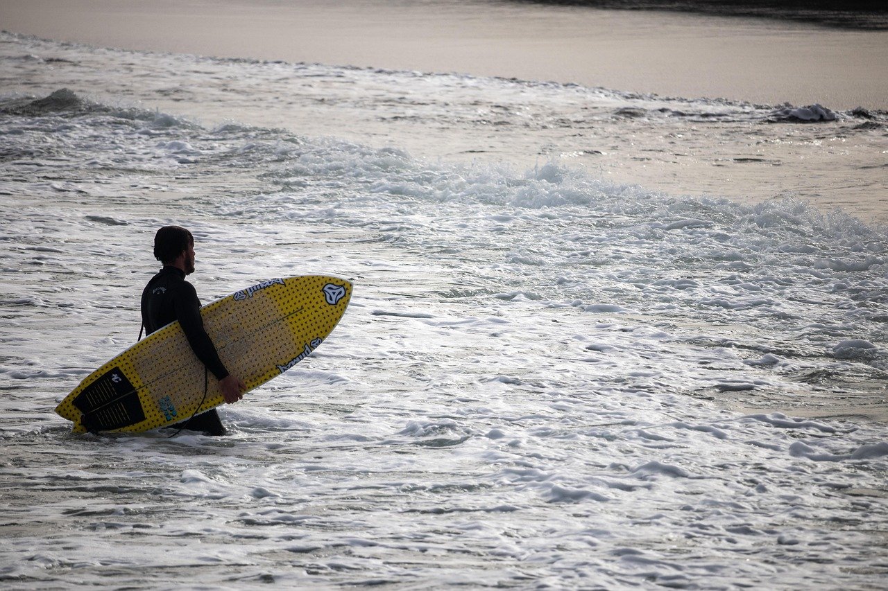 Surfer walking along a beach carrying a board