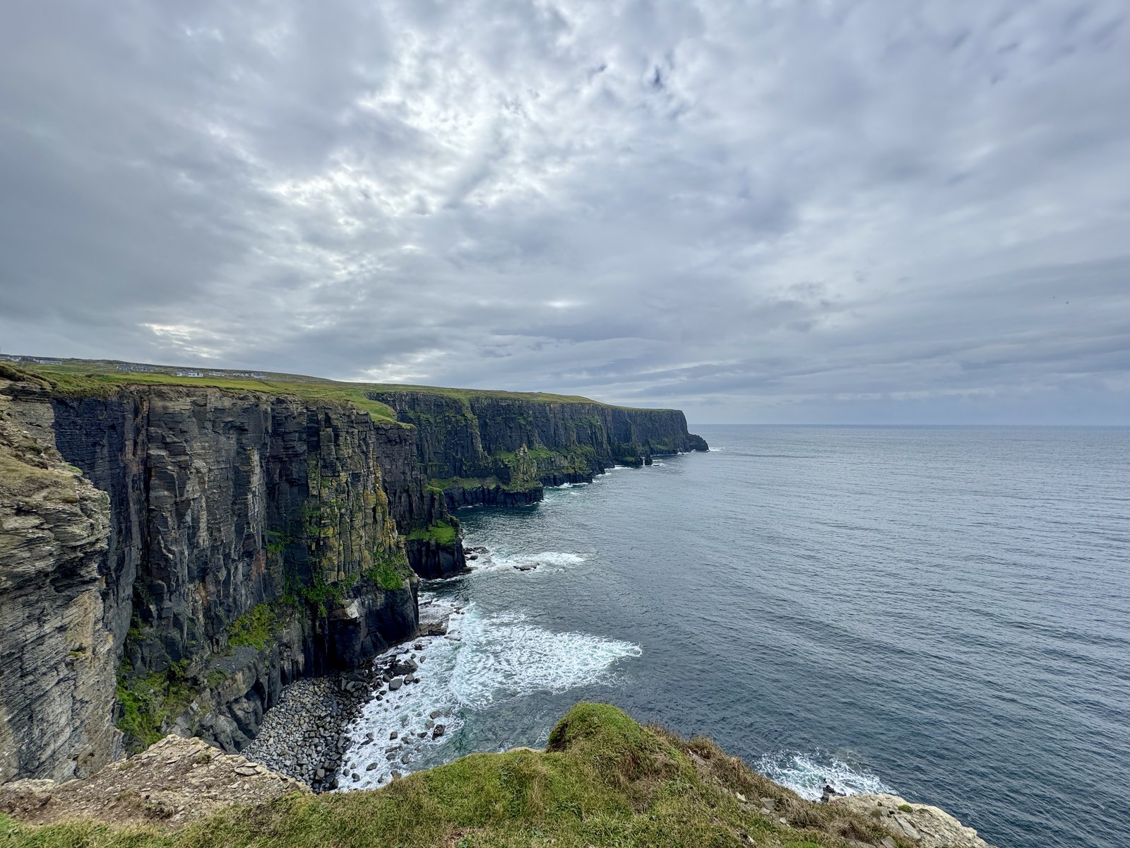 The Cliffs of Moher stretching along the coast under a grey Atlantic sky