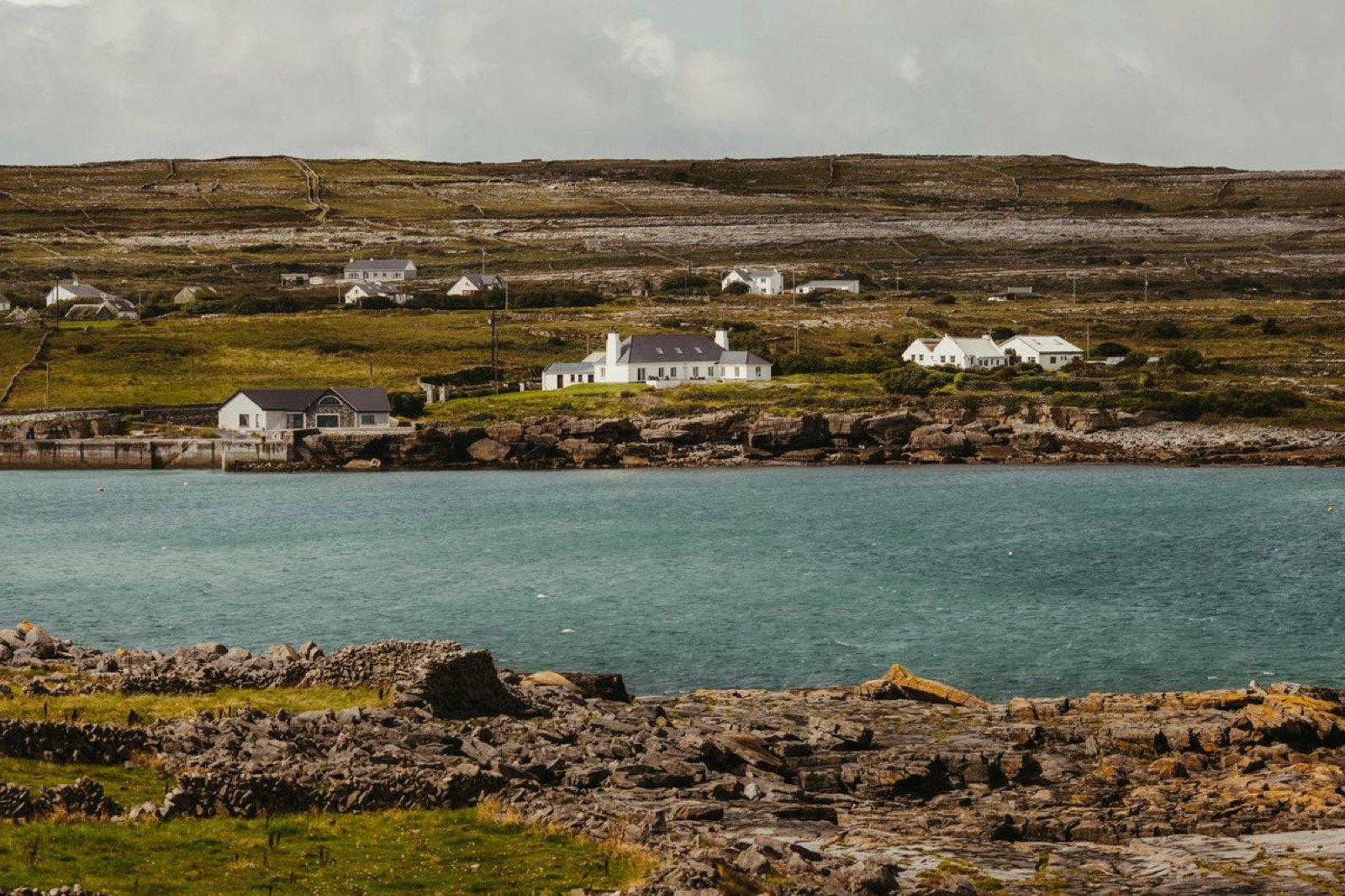 White cottages clustered along an Aran island shore across a blue inlet