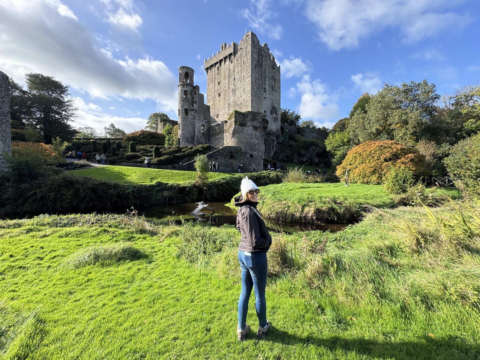 Woman walking the green grounds below Blarney Castle tower