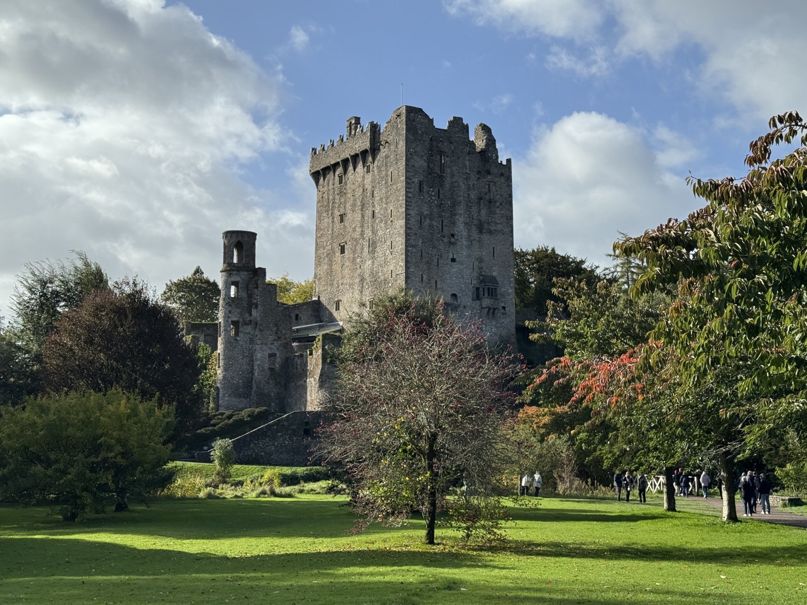 Blarney Castle tower seen across the lawn with visitors on the path