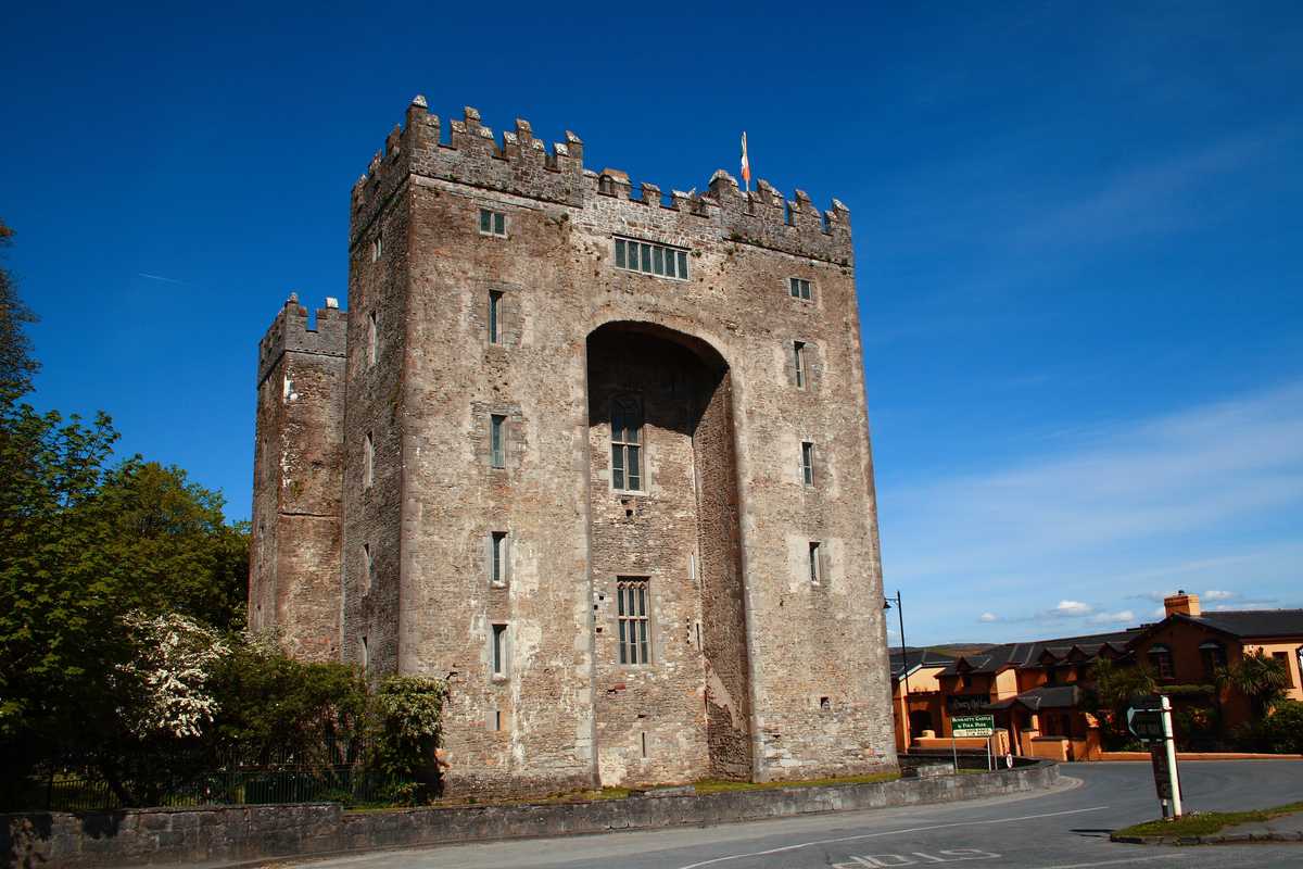 Bunratty Castle tower house with its tall central archway under a blue sky in County Clare
